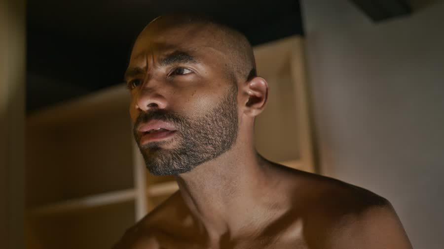 A man with a beard examining his skin in soft light