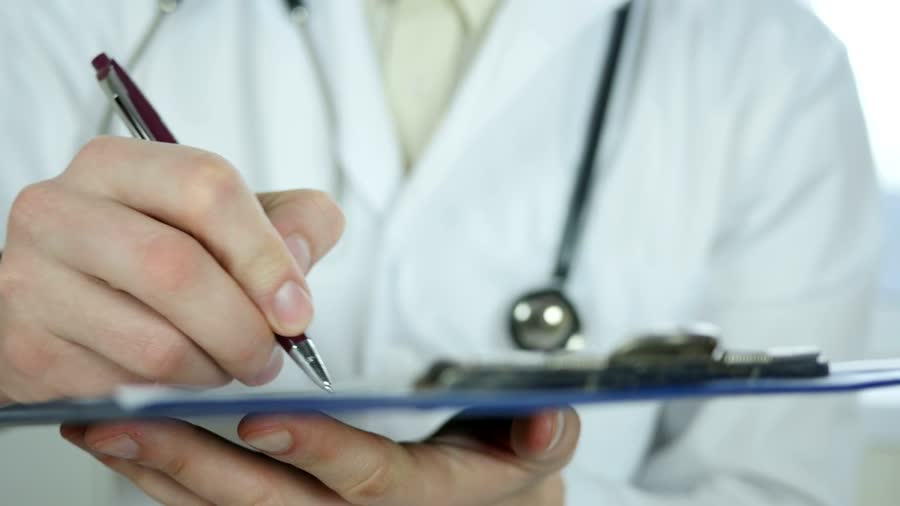 A doctor writing notes on a clipboard